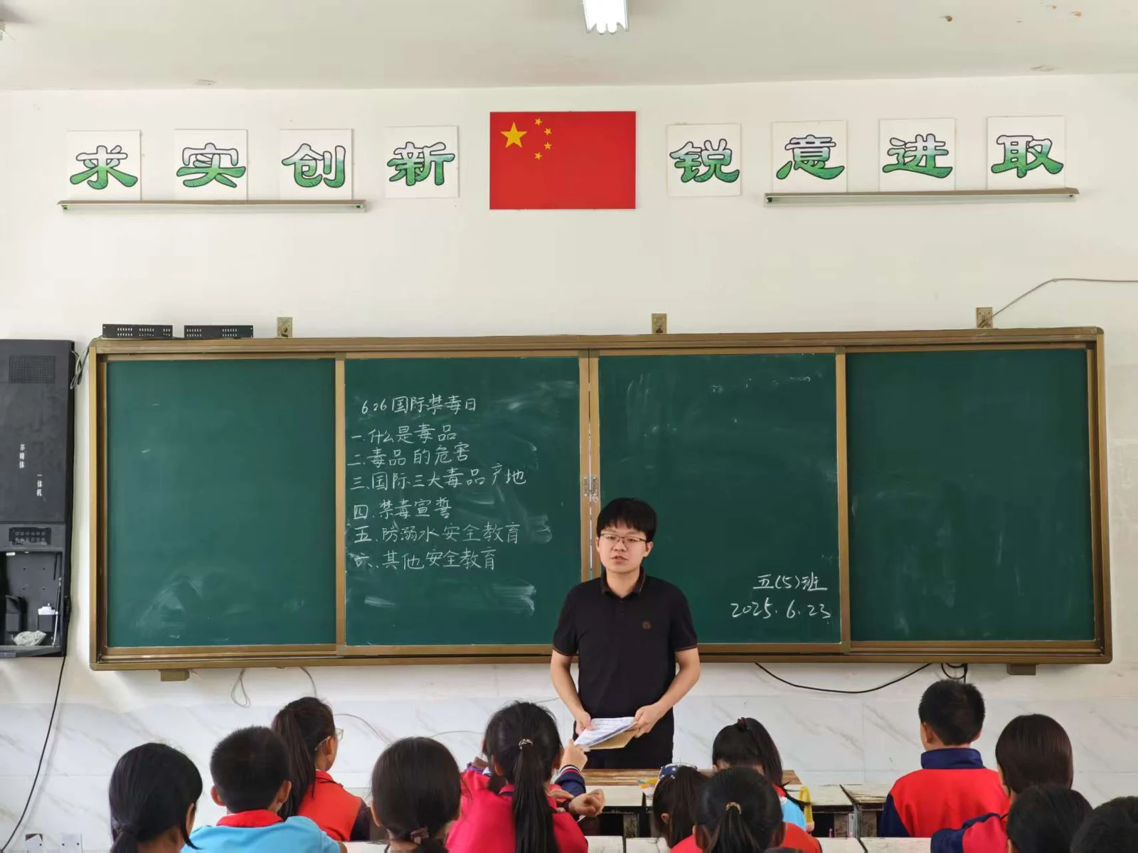 A volunteer teaching students in a classroom with a blackboard