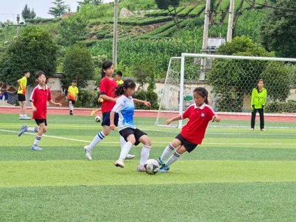 Students and volunteers playing football on a green pitch