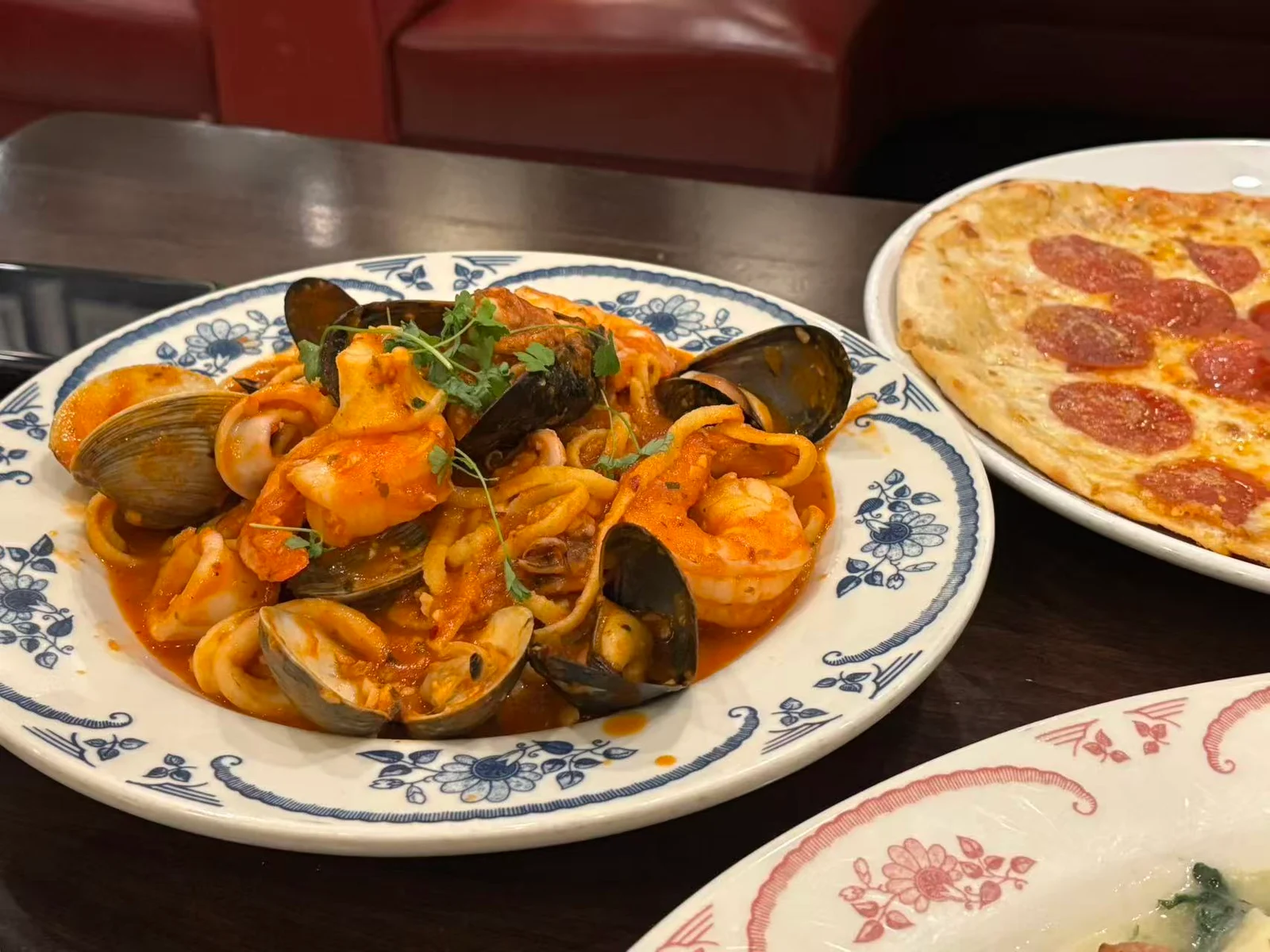 A restaurant table with seafood pasta and pizza